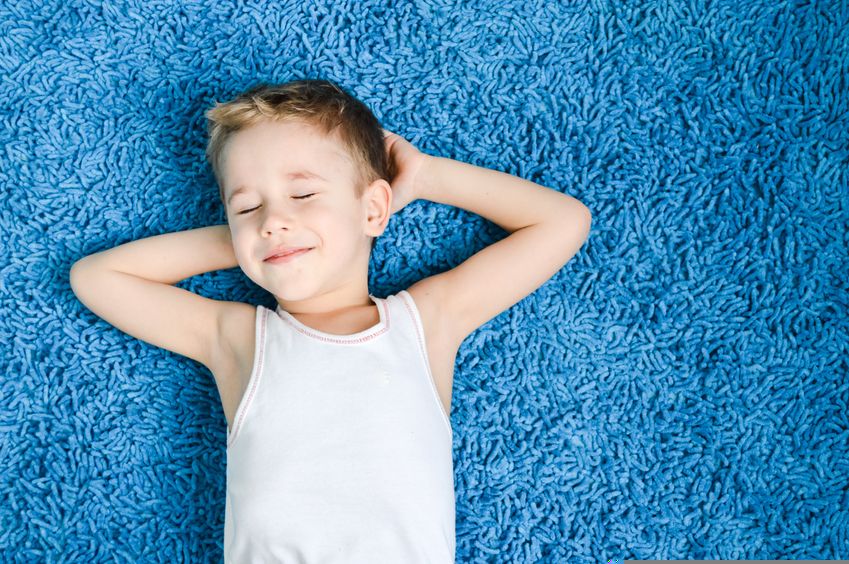 happy boy smiling kid on blue carpet in living room at home