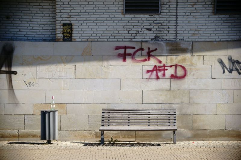 62445712 - a park bench is on the facade of a building, which is scribbled with graffiti tags.