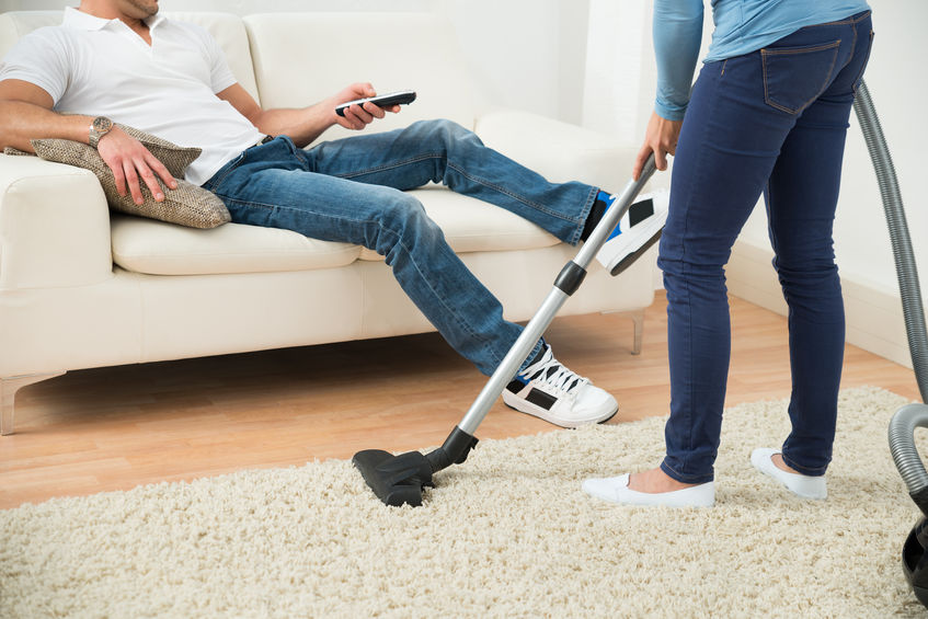 41317965 - close-up of a woman cleaning carpet in front of man sitting on couch